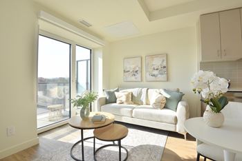A living room with a white couch, a coffee table, and a large window